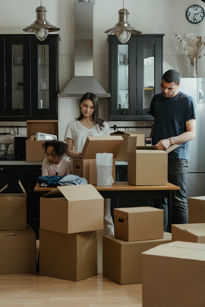 team-03 Family unpacking boxes together in a modern kitchen after moving into a new home.